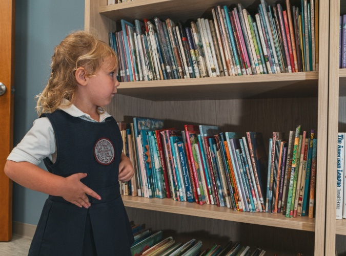 private school student in front of a book shelf at Saint Gregory's School in Loudonville, NY