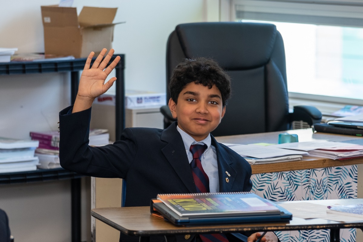 private school student raising his hand during class