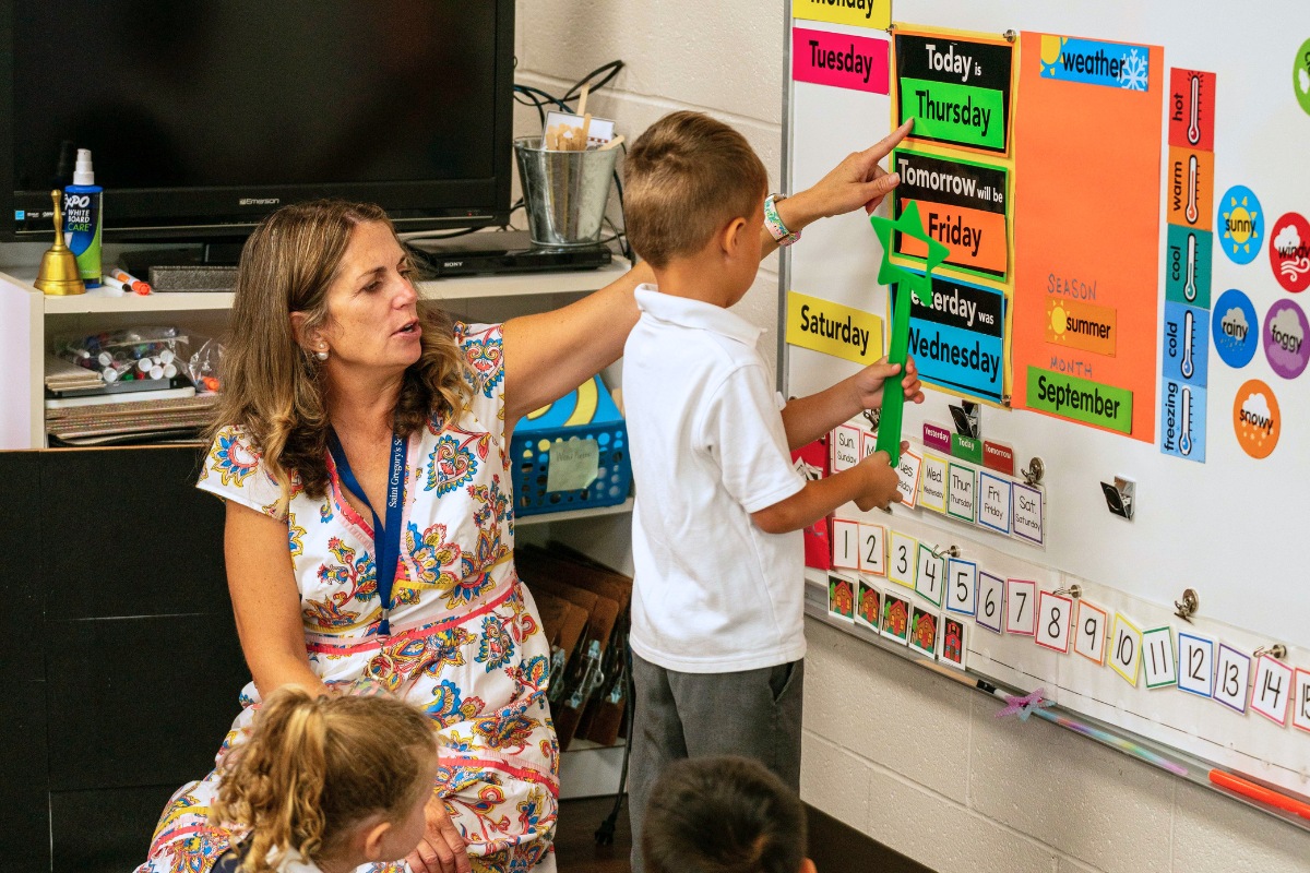 Pre-K Teacher explaining something to a private school student during class